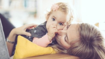小女孩吸拇指时 躺在她妈妈身上 她妈妈正在想 如何停止拇指吸